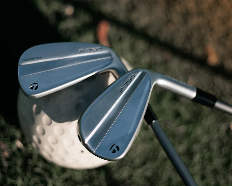 Golf iron resting beside a ball on short grass